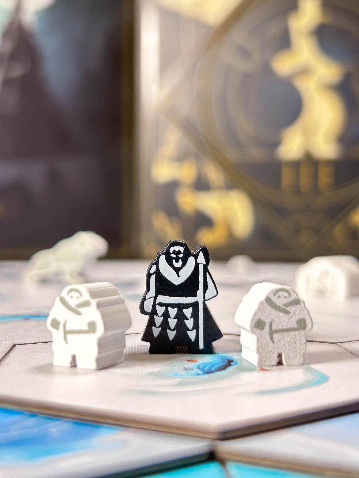 Three stylized game meeples for ICE Collector photographed in a tabletop setting with a blurred game board in the background.