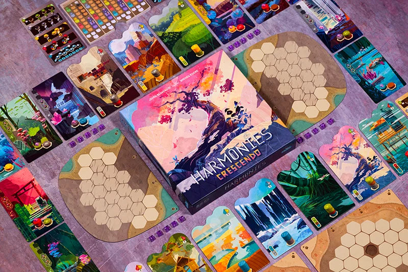 Harmonies Crescendo board game spread out on a textured surface, featuring a central illustrated game box surrounded by colourful cards, hexagonal tiles, and game components.